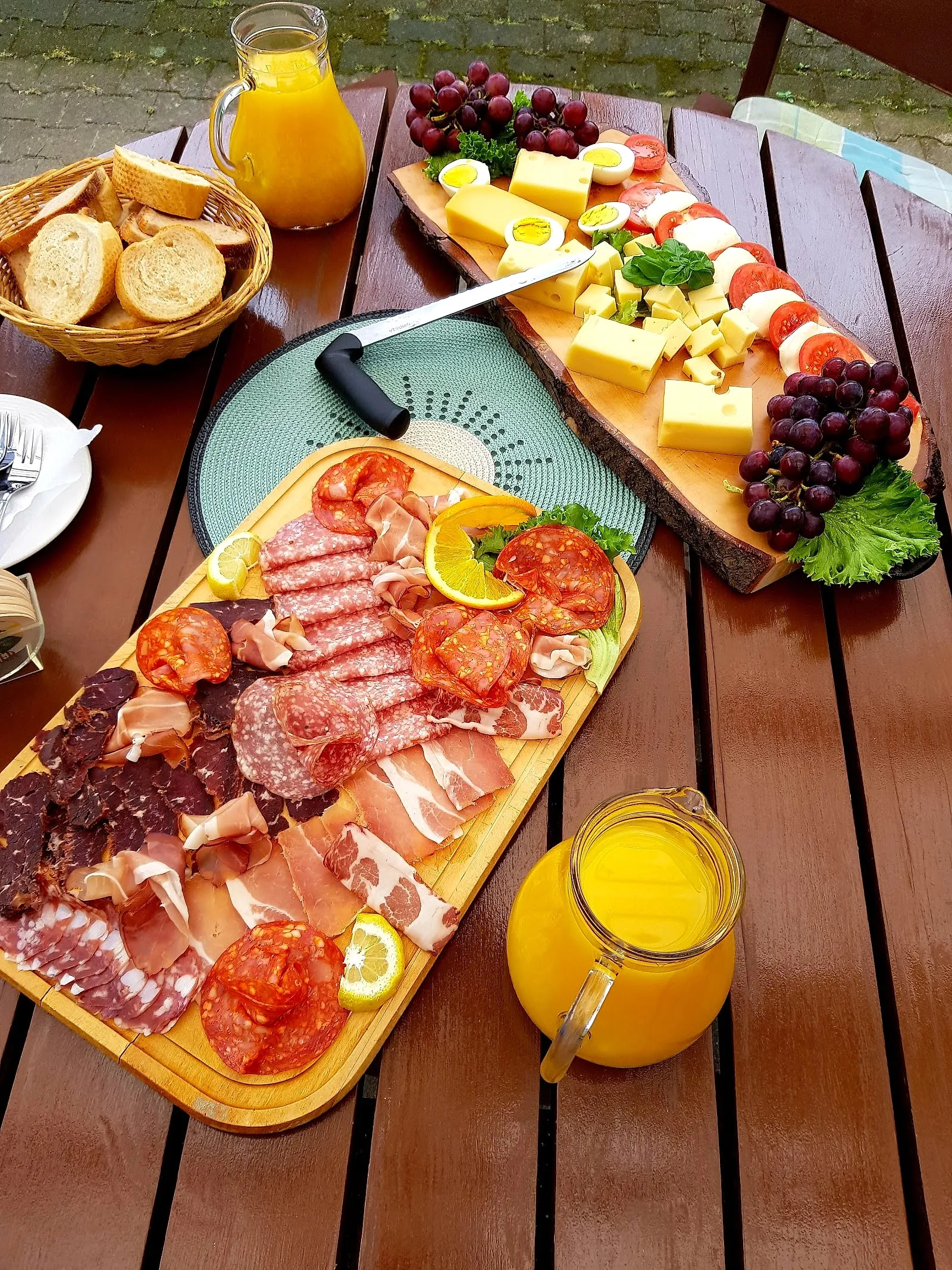 Vesperplatte mit Wurst, Käse, Brot und Trauben auf einem Holztisch im Biergarten